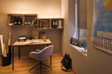 Cozy workspace with wooden desk, grey chair, and warm white LED wall lighting for home office.