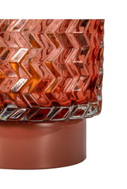 Close-up of red glass lampshade with zigzag pattern and red metal base for home lighting decor