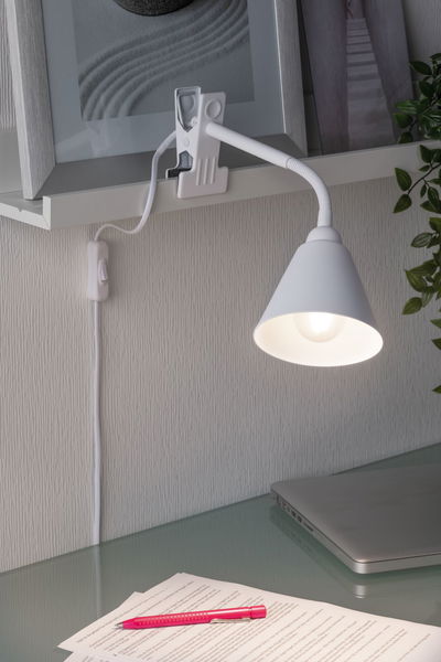 Witte metalen klemlamp met flexibele arm boven bureau met laptop en documenten voor leeslicht.