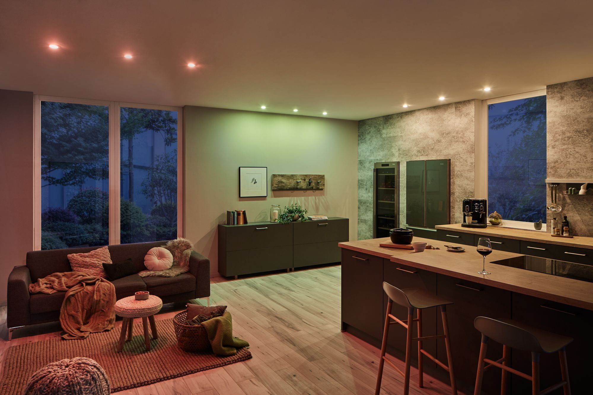 Salon avec spots LED blanc chaud et colorés, cuisine moderne avec îlot et coin canapé confortable.