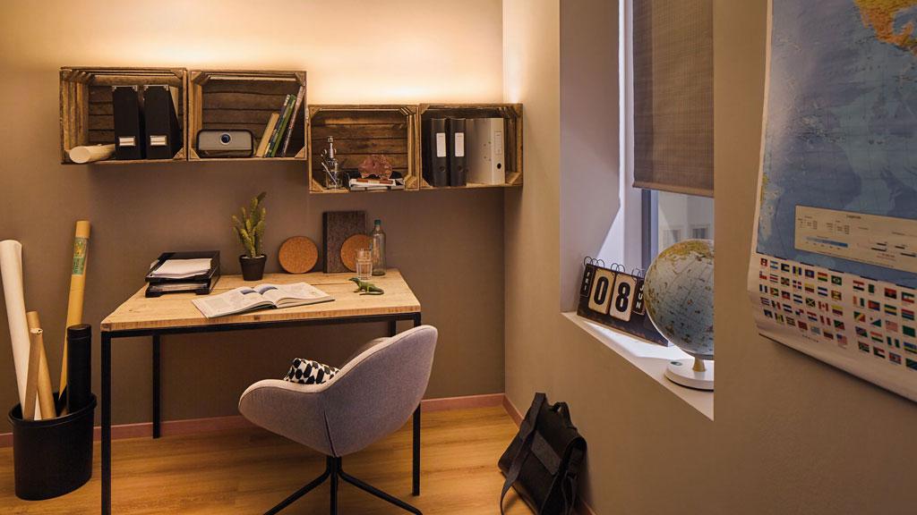 Bureau confortable avec étagères en bois, bureau clair et chaise grise sous lumière chaude.