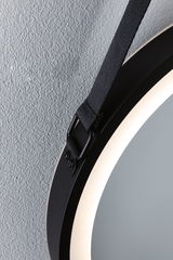 Round black LED mirror with integrated light and black hanging strap on textured wall