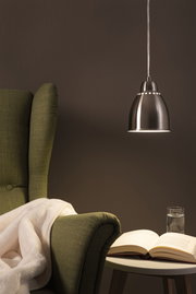 Moderner Edelstahl-Hängeleuchter mit warmweißem Licht über grünem Sessel und Lesetisch im Wohnzimmer