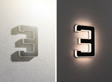 Modern LED wall light shaped as number 3 in black and white plastic with indirect lighting effect.