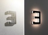 Applique murale LED moderne en forme de chiffre 3 en plastique noir et blanc avec éclairage indirect.