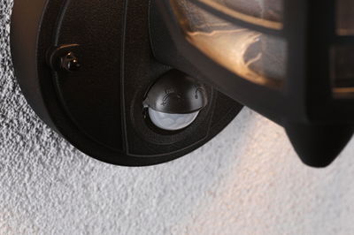 Nahaufnahme eines schwarzen Bewegungsmelders aus Kunststoff an einer Außenwandleuchte für LED-Beleuchtung