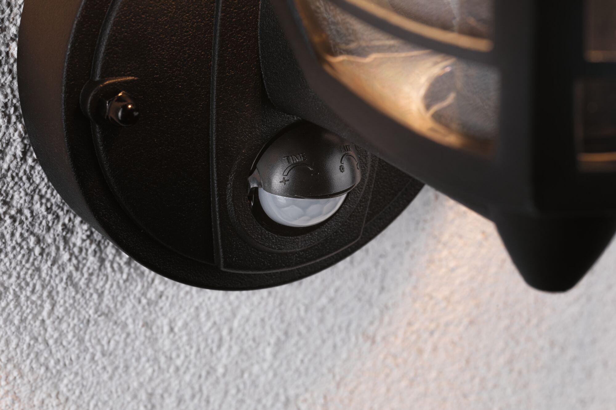 Nærbillede af sort plast bevægelsessensor på udendørs væglampe til LED-belysning