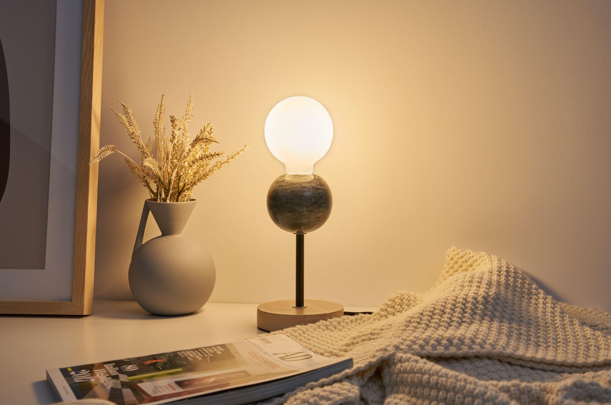 Modern table lamp with wooden base and black metal stem, warm white light, decorative in living room.