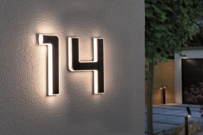 Husnummer 14 i sort materiale med integreret LED-belysning på hvid udvendig væg