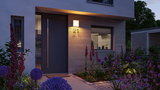 Modern outdoor wall light with warm white glow on wooden facade by front door and house number 21 at dusk