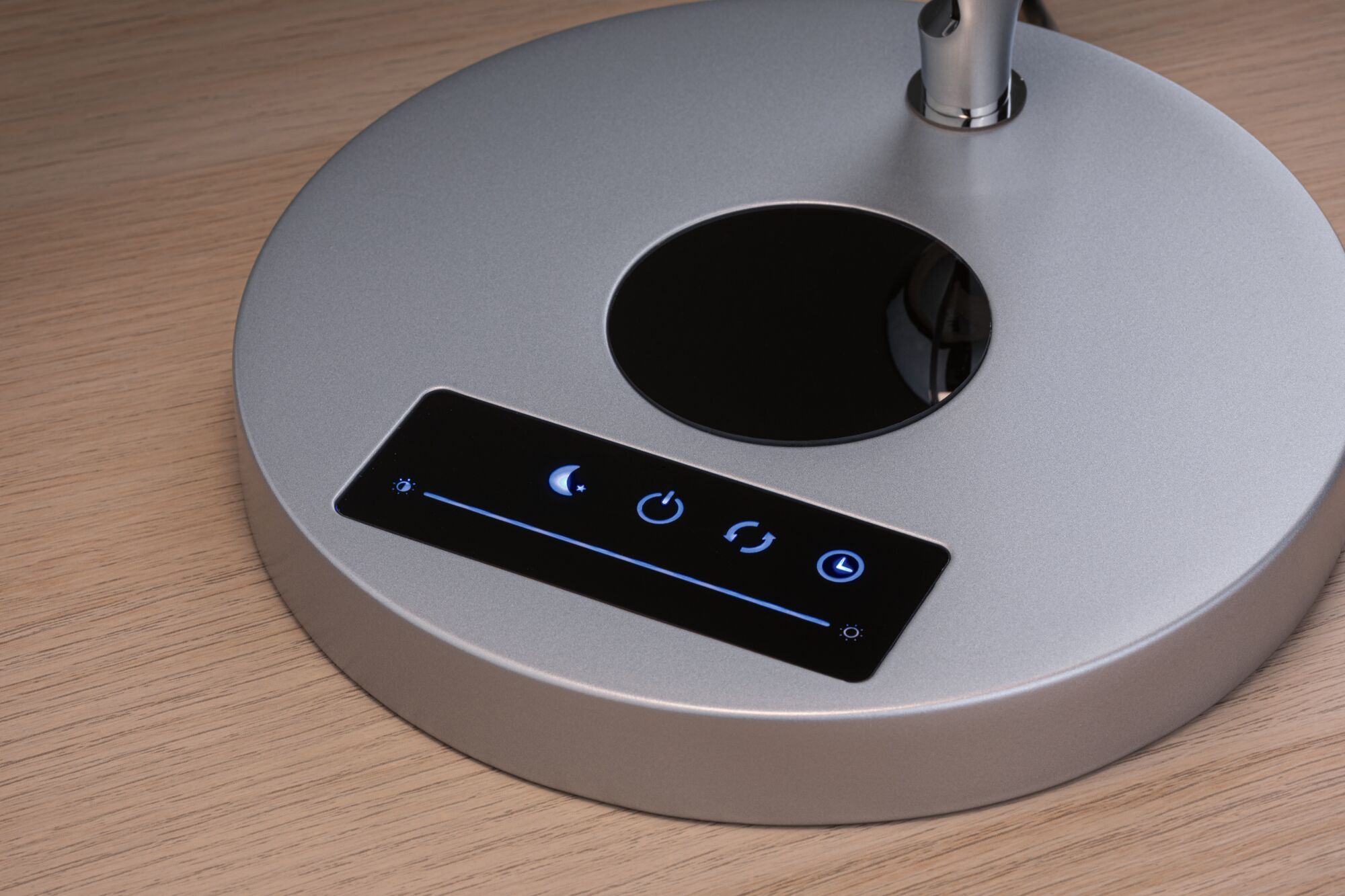 Base de lampe ronde argentée avec panneau tactile et icônes de réglage de lumière sur surface en bois
