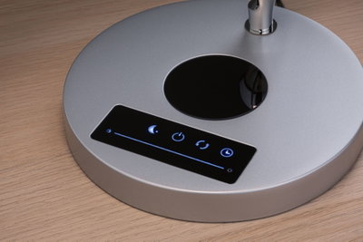 Base de lampe ronde argentée avec panneau tactile et icônes de réglage de lumière sur surface en bois