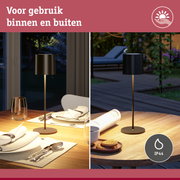 Zwarte vloerlamp met metalen voet op houten tafel, geschikt voor binnen- en buitengebruik met IP44 bescherming