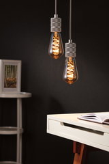 Two hanging vintage light bulbs with warm glow and grey metal sockets against dark background.