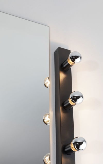 Black wall lamp with three silver bulbs beside mirror, modern LED wall light for bathroom and hallway