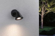 Applique murale extérieure noire en métal avec lumière LED blanc chaud sur mur blanc dans un jardin