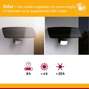 Zwarte solar lamp met bewegingssensor aan witte muur, dag- en nachtzicht, energiezuinige buitenverlichting