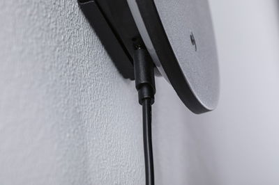 Close-up of black cable connection on grey plastic wall mount with textured surface