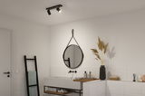 Modern bathroom with black ceiling light, round mirror, and white sink with wooden shelf