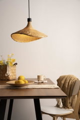 Hängelampe aus geflochtenem Naturmaterial in Beige über Holztisch mit Zitronen und Becher