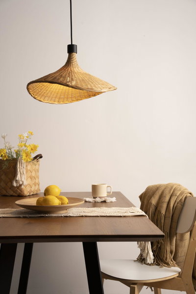 Hängelampe aus geflochtenem Naturmaterial in Beige über Holztisch mit Zitronen und Becher