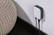 Petit appareil réseau blanc et gris fixé au mur avec deux câbles, accessoire moderne pour réseau domestique