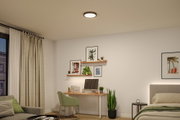 Rundes Deckenlicht mit schwarzem Rahmen aus Metall in modernem Schlafzimmer mit Schreibtisch und Pflanzen