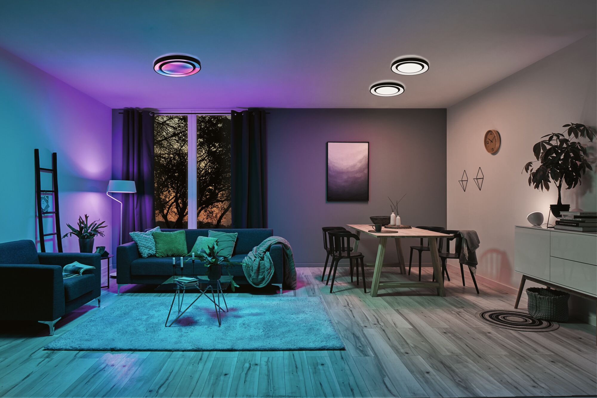 Modernes Wohnzimmer mit blauen und violetten LED-Deckenleuchten und gemütlicher Sitzgruppe mit grünem Akzent.
