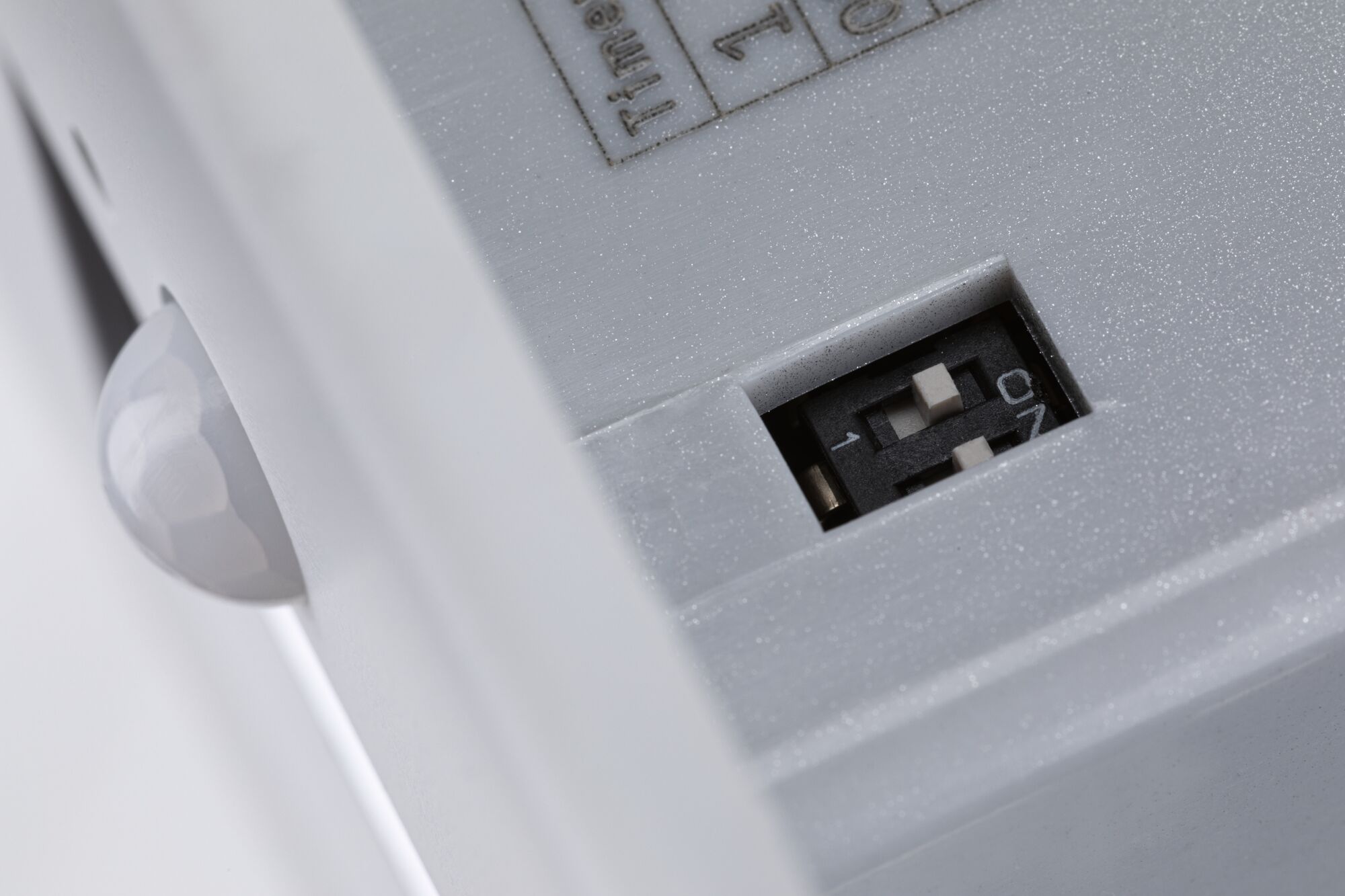 Nahaufnahme eines weißen Kunststoffgehäuses mit Schalter und Sensorkugel für Beleuchtungstechnik