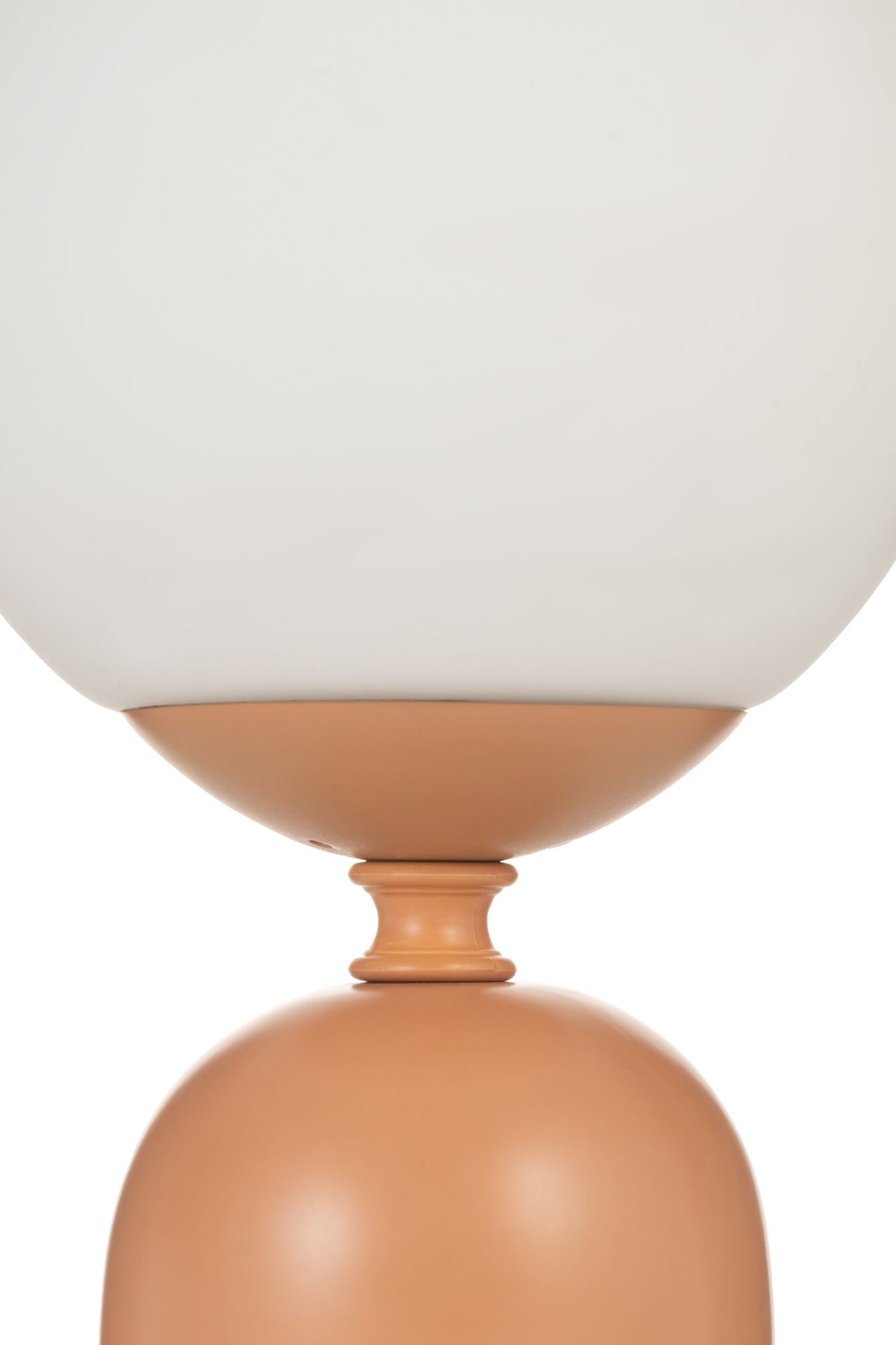 Gros plan d'une lampe de table moderne avec abat-jour en verre blanc et base en métal terracotta mat