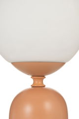Close-up of modern table lamp with white glass shade and matte terracotta metal base for interior lighting