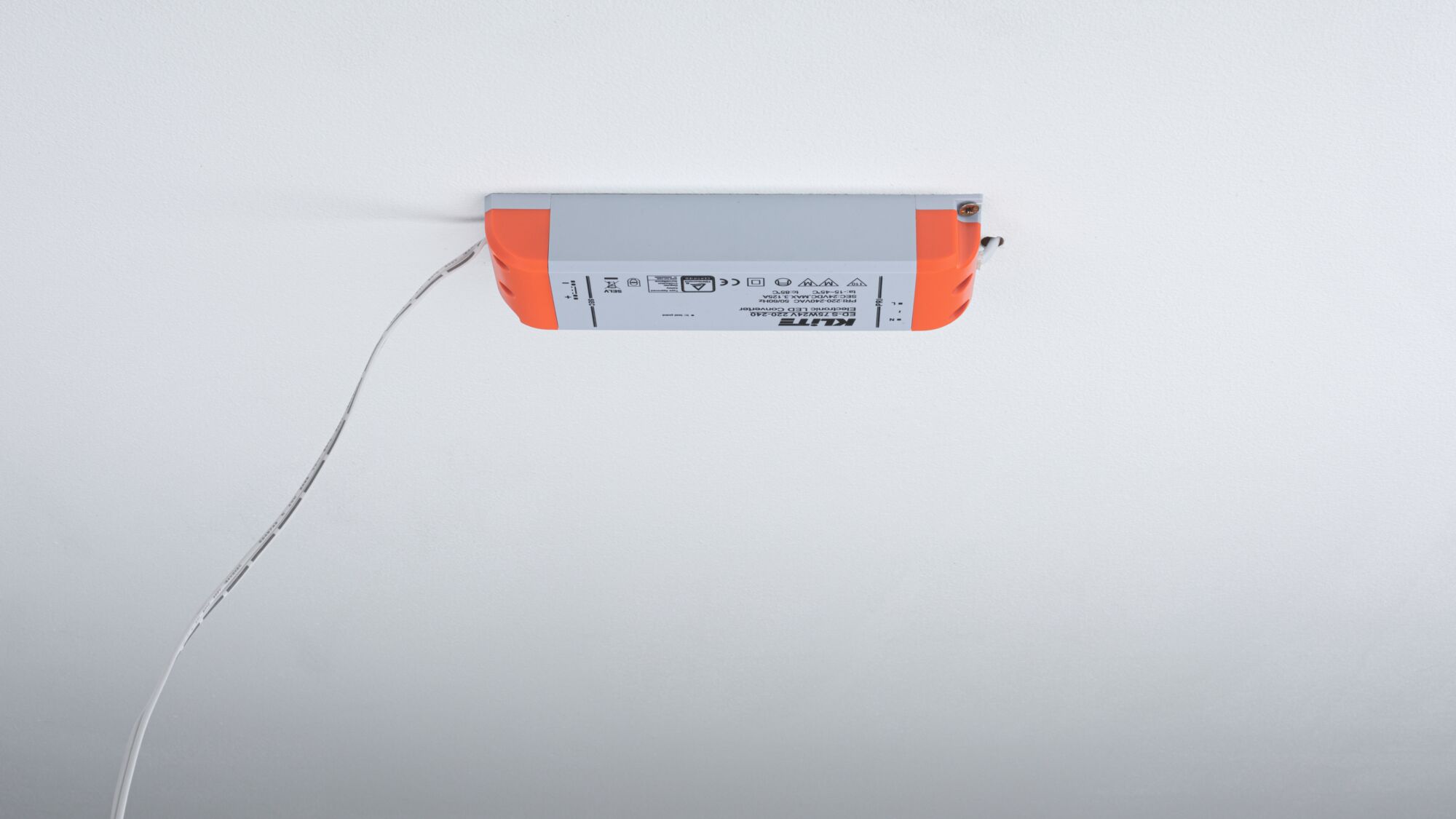 LED-Treiber mit grauem Gehäuse und orangen Endkappen an weißer Decke montiert, Stromkabel sichtbar