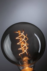 Nærbillede af en pære med spiralformet LED-filament, der udsender varmt lys til dekorativ belysning