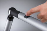 Main appuyant sur interrupteur noir d'une lampe de lecture LED en aluminium argenté avec articulation flexible.