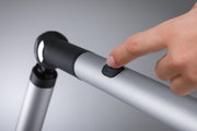 Hand pressing black switch on silver aluminum LED reading lamp with flexible joint for office use.