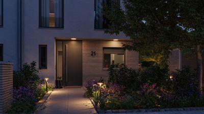 Beleuchteter Hauseingang mit moderner Außenbeleuchtung und Gartenweg mit LED-Pollerleuchten in warmweiß.