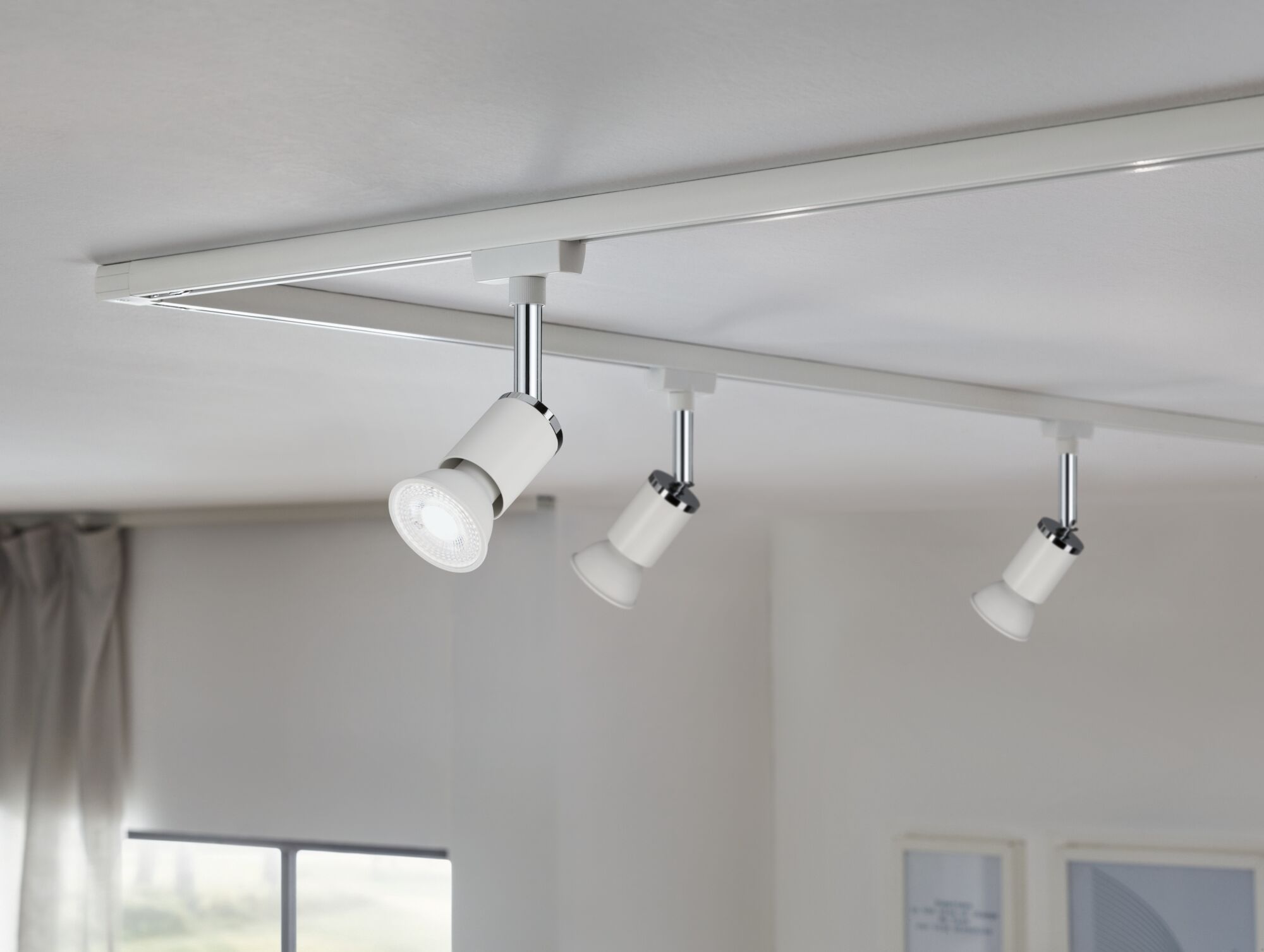 Tre hvide LED-spotlights på en hvid skinne til fleksibel loftsbelysning i et moderne rum.