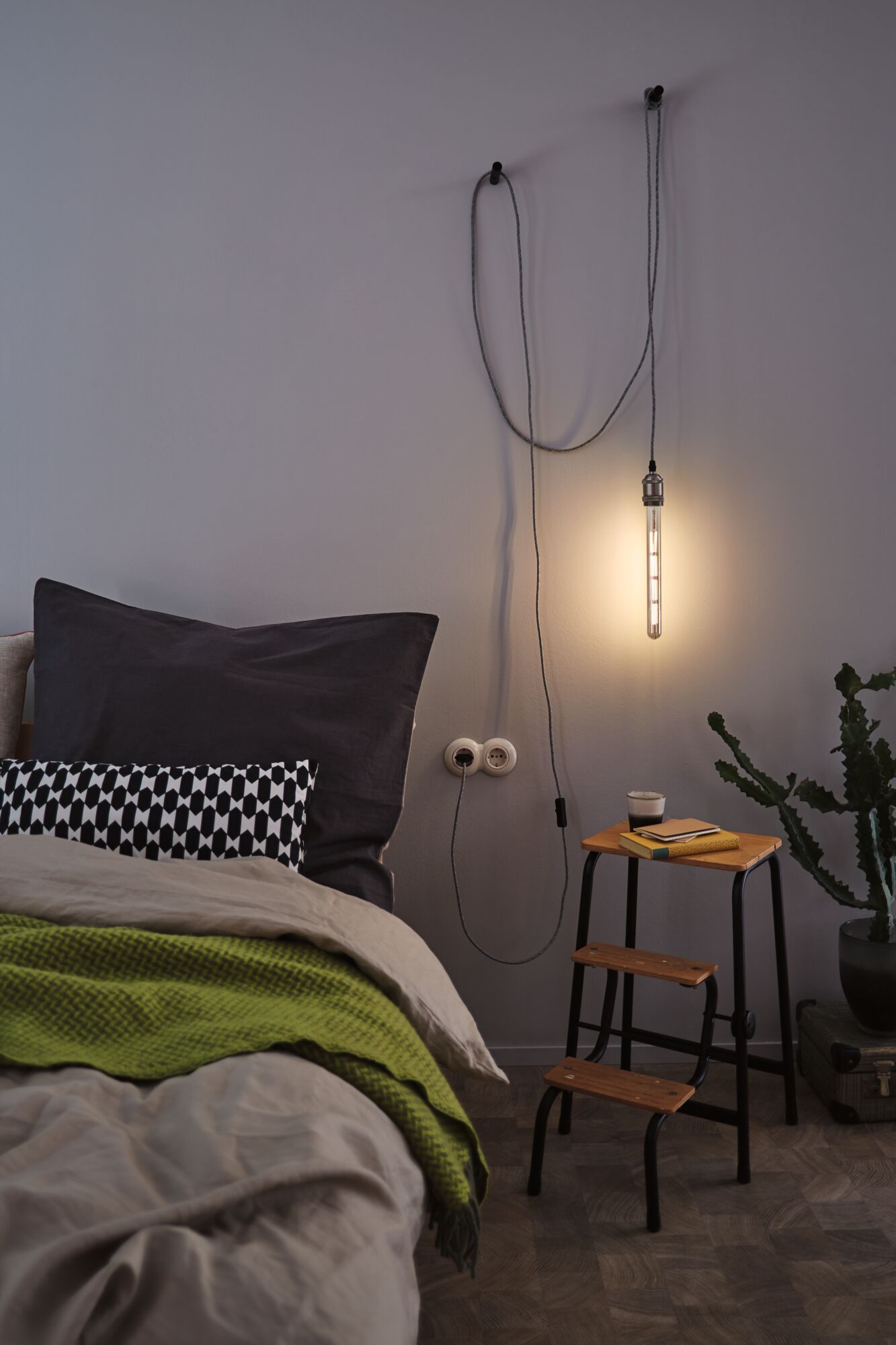 Bedroom with hanging warm white LED tube light, wooden step stool and green blanket for cozy lighting