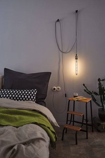 Bedroom with hanging warm white LED tube light, wooden step stool and green blanket for cozy lighting