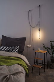Schlafzimmer mit hängender LED-Röhre in warmweiß, Holztrittleiter und grüner Decke für gemütliche Beleuchtung