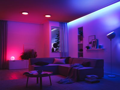 Moderne stue med LED-loftslamper og farverig stemningsbelysning for en hyggelig atmosfære.