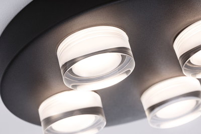 Moderne loftlampe med fire runde glaslamper på sort metalplade til opholdsrum.