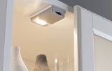 Compact silver LED under-cabinet light with warm white illumination for furniture and display cases.