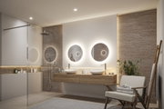 Modernes Badezimmer mit beleuchteten runden Spiegeln, Holzwaschtisch und natürlicher Steinwandbeleuchtung
