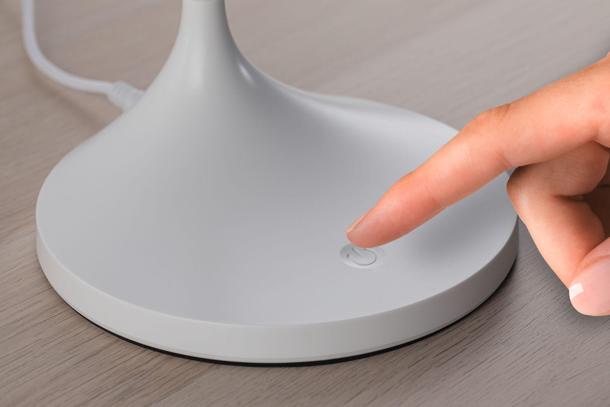 White plastic lamp base with touch-sensitive power button on wooden surface
