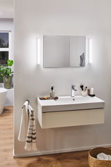 Salle de bain moderne avec lavabo mural blanc, miroir et deux appliques LED fines pour éclairage de salle de bain
