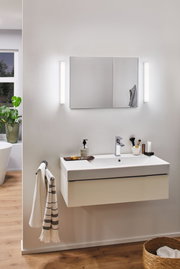 Modern bathroom with white ceramic sink and LED wall lights beside mirror