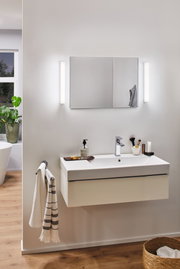 Moderne badeværelse med hvid keramisk vask og LED-væglamper ved spejl