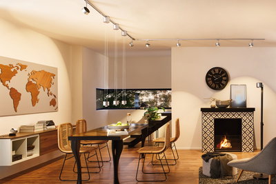 Modern dining room with black wooden table, rattan chairs, and Paulmann URail silver track lighting system.