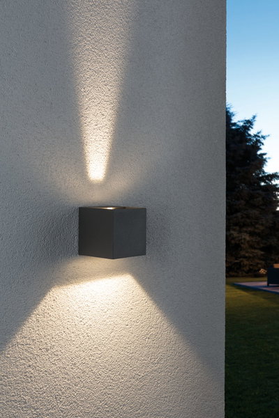Black square outdoor wall light in metal with warm white up and down lighting effect.